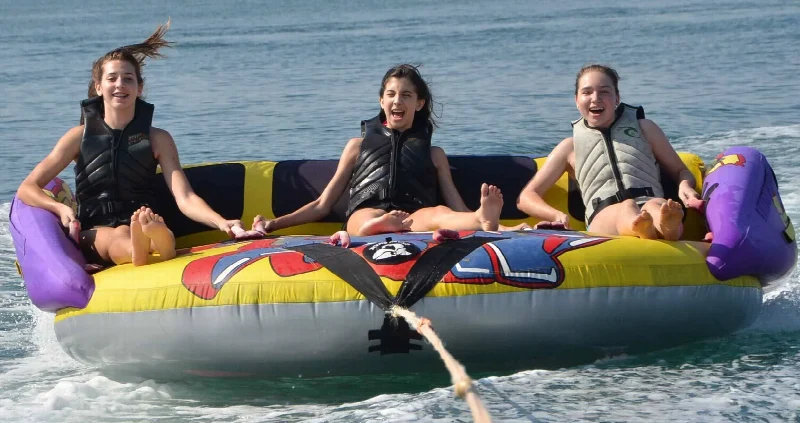Three riders wearing life jackets on a colourful inflatable donut towable