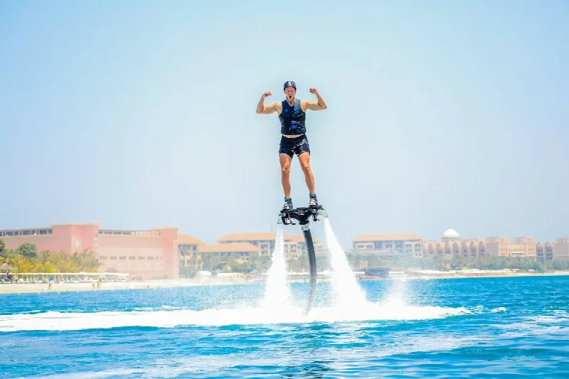 A rider on a flyboard above the sea with Dubai waterfront buildings behind